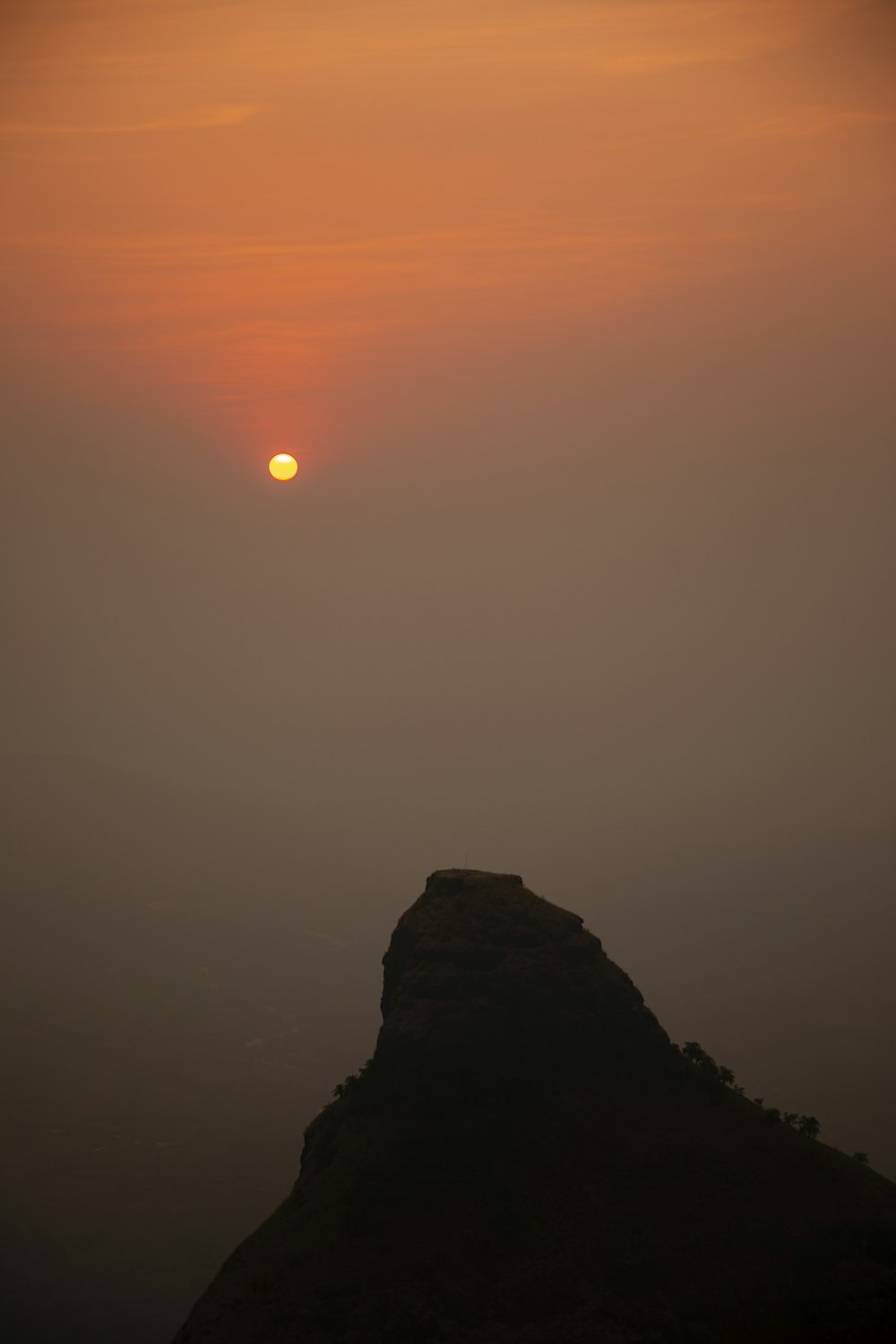 the sun is setting over a mountain in the fog