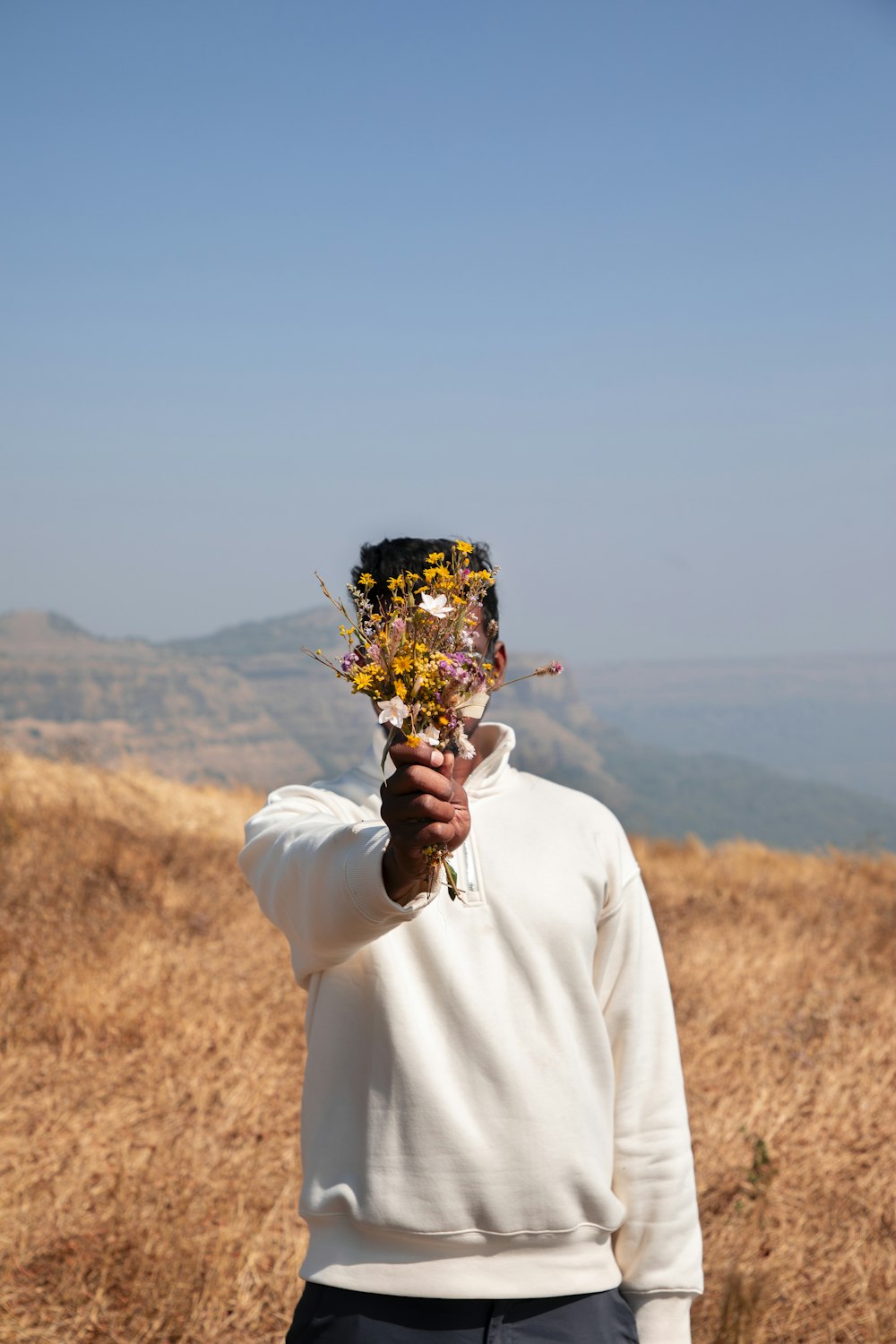 a man holding a bunch of flowers up to his face