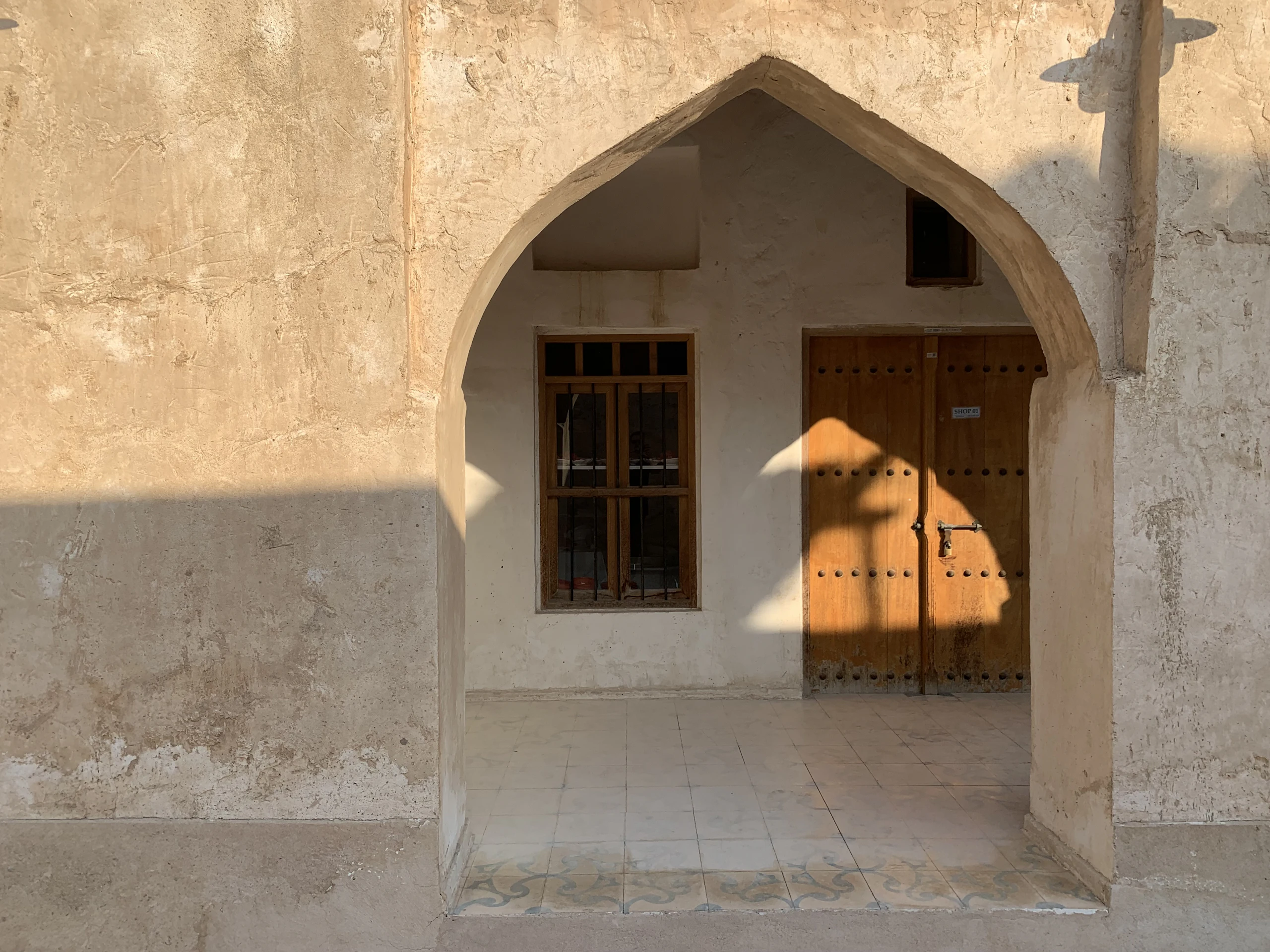Lime-plastered arches and timber doors in soft light