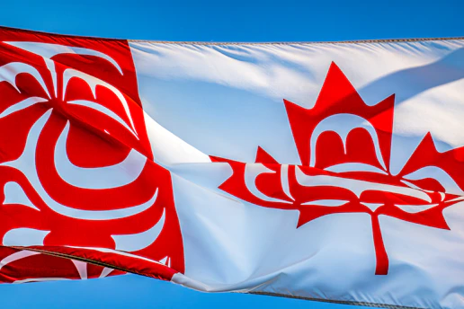 a canadian flag flying in the wind with a blue sky in the background