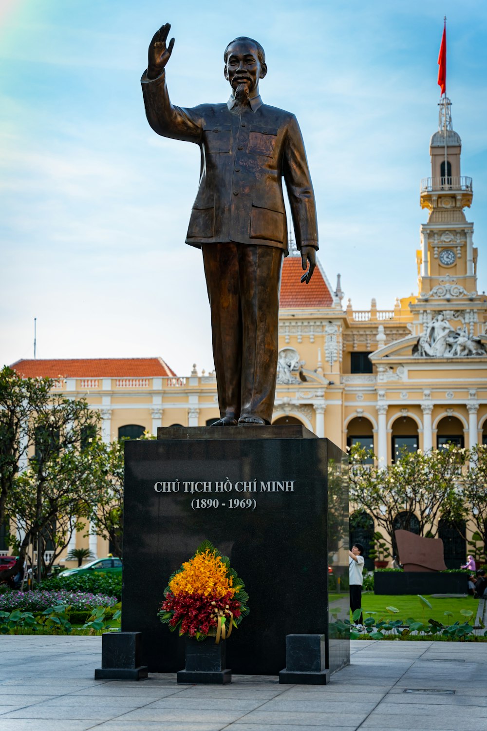 a statue of a man in a suit with a rainbow in the background