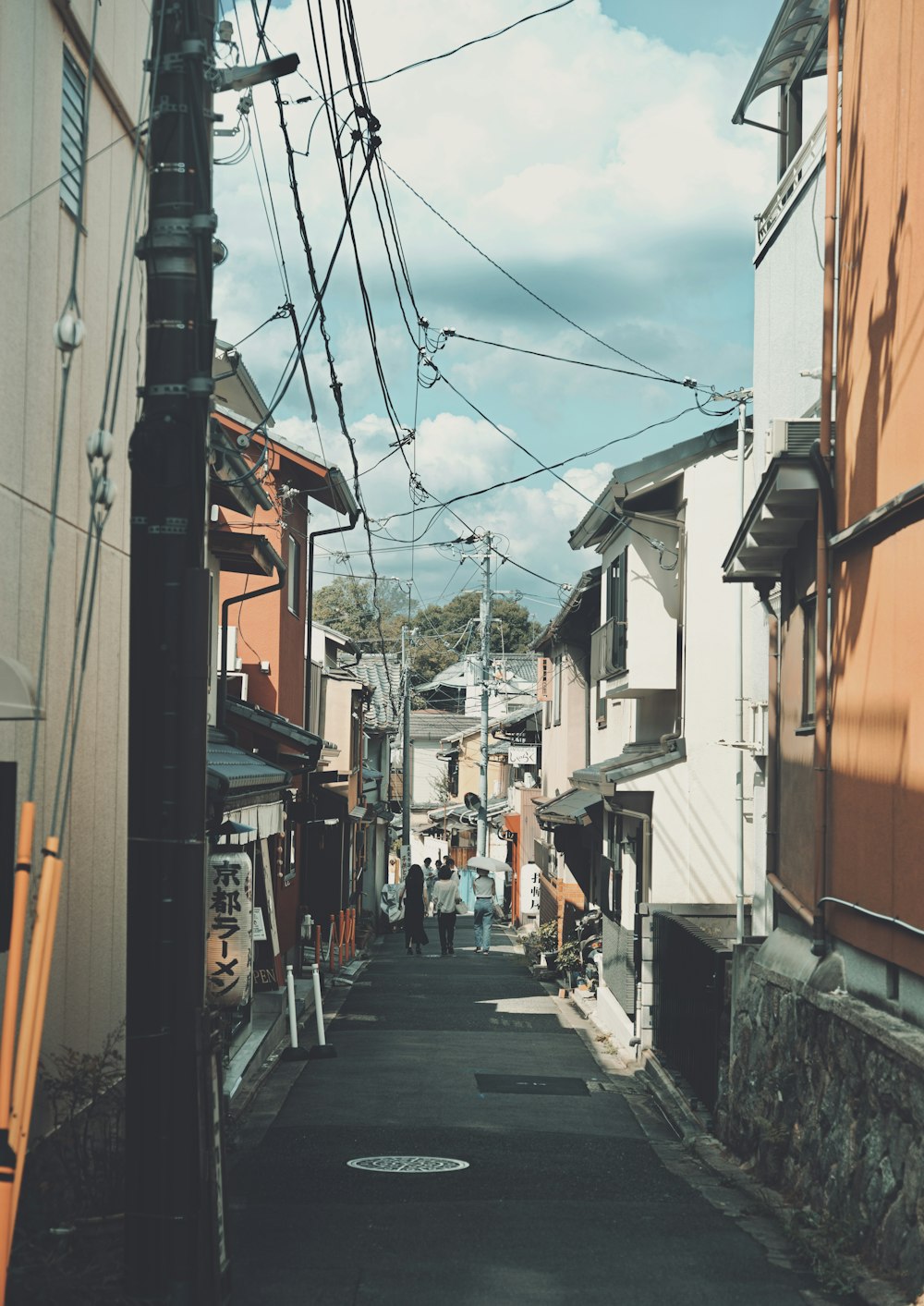 a narrow city street lined with buildings and power lines