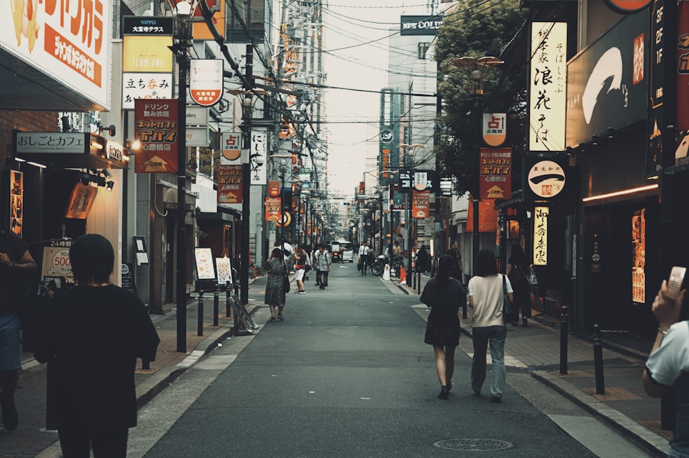 a group of people walking down a street next to tall buildings