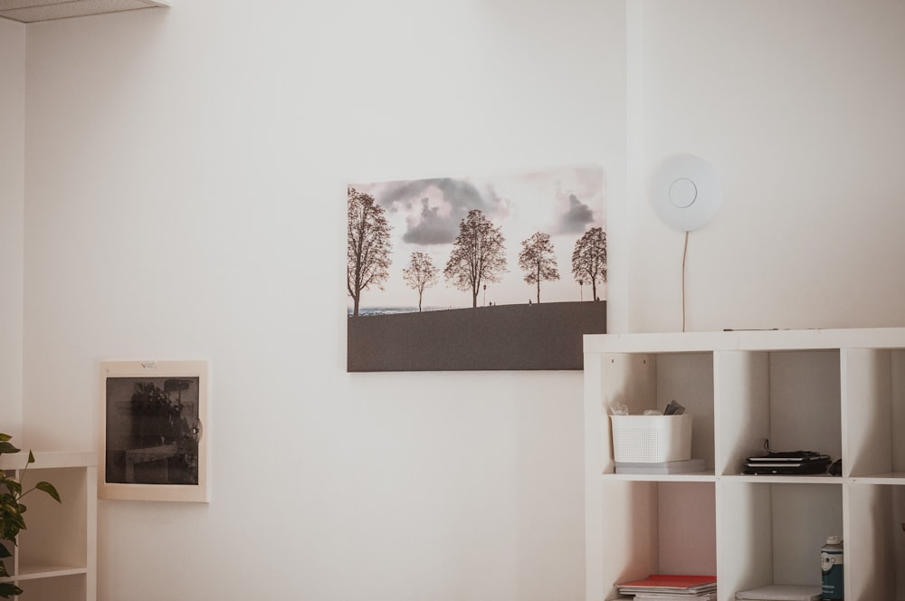 a room with a book shelf and a painting on the wall