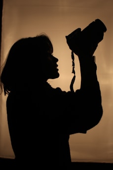 a silhouette of a woman holding a camera