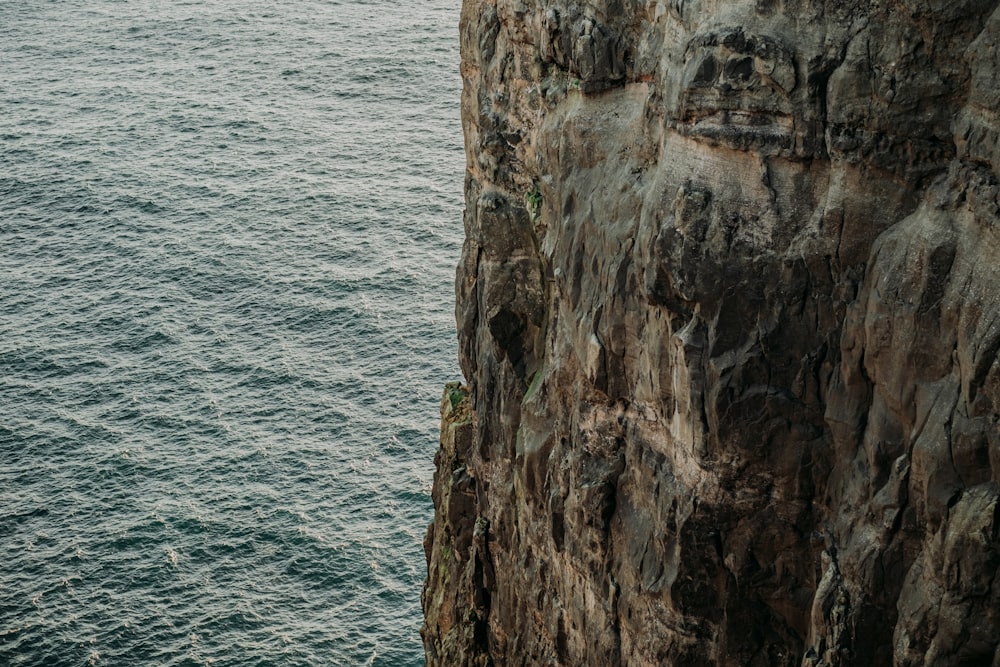 a man standing on the edge of a cliff next to the ocean