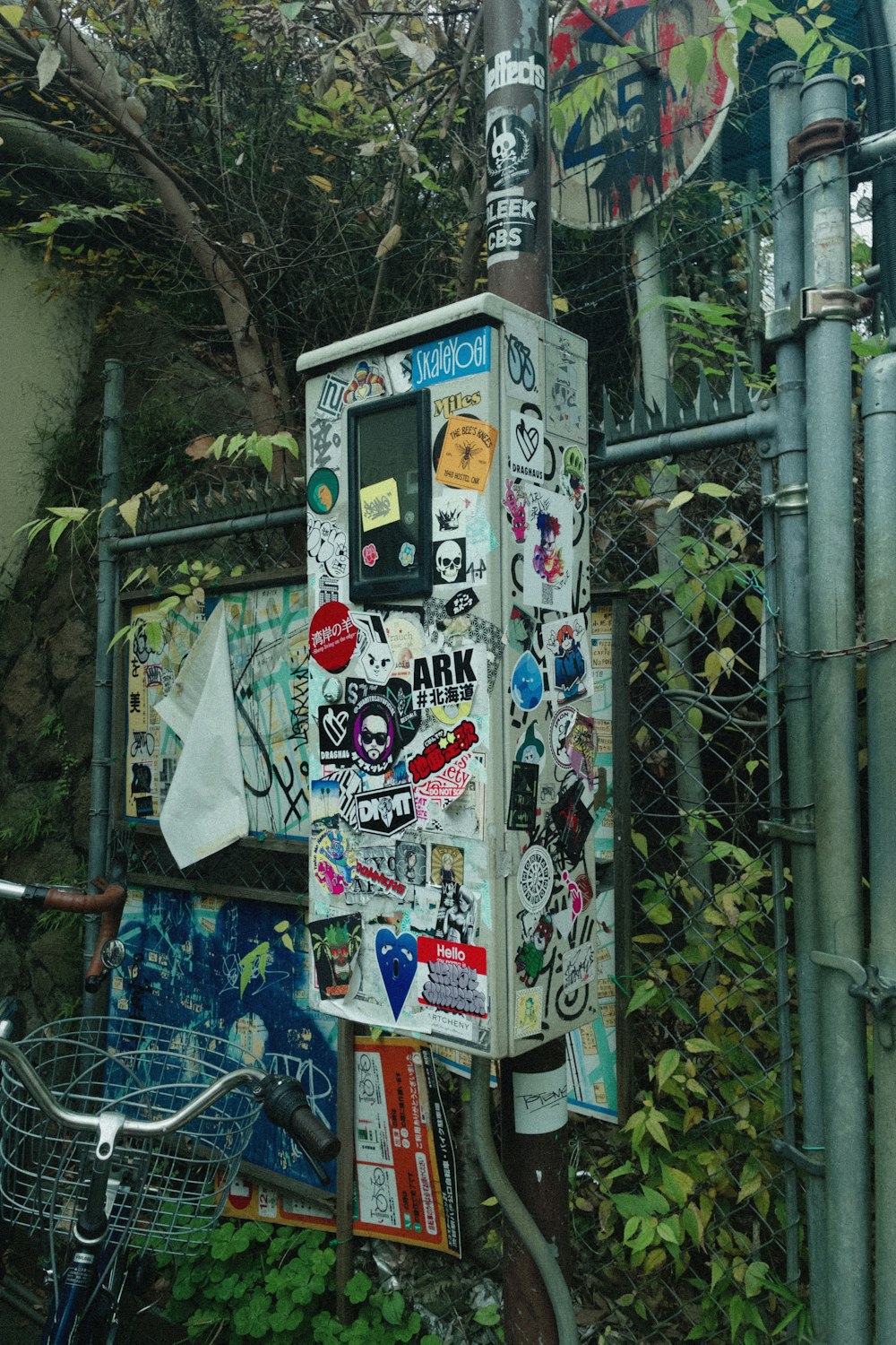 a parking meter covered in stickers next to a fence