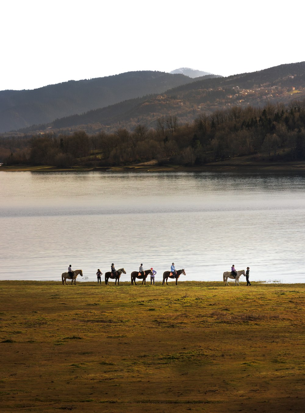 a group of people riding horses across a field