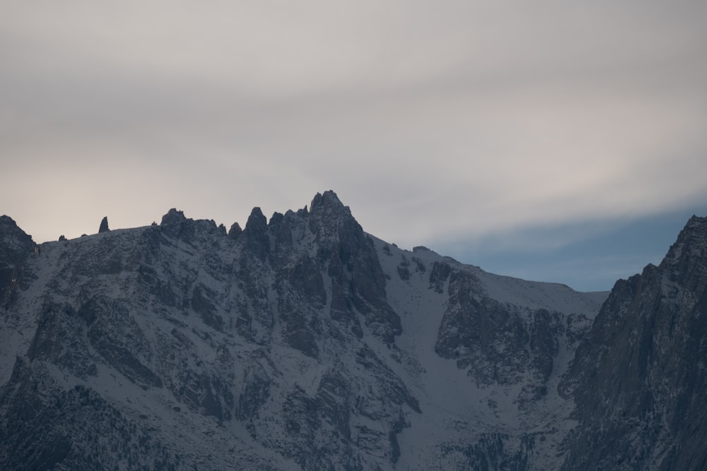 a very tall mountain covered in snow under a cloudy sky