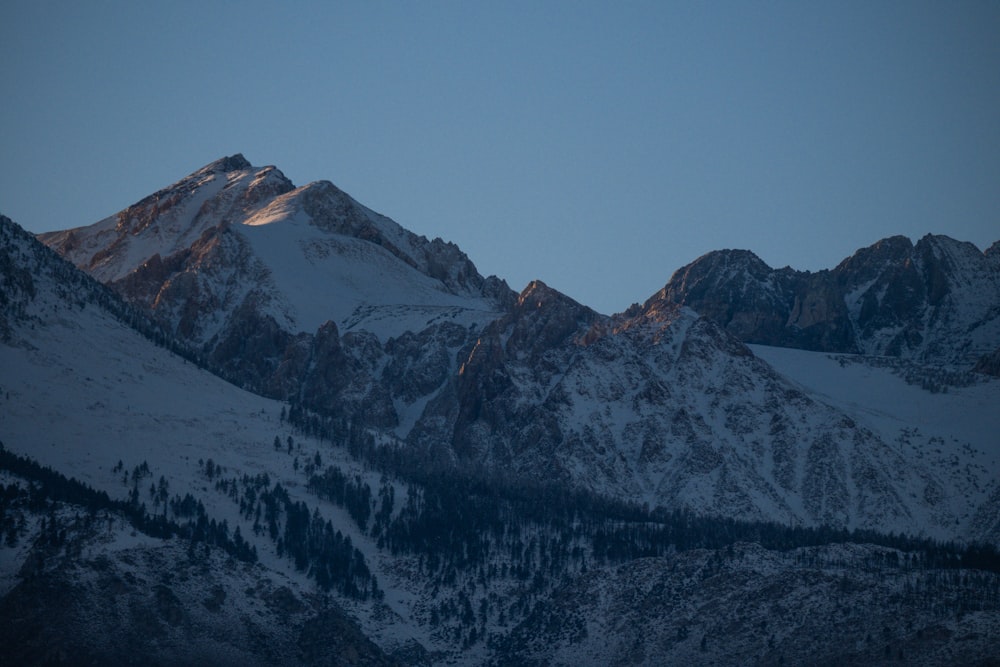 a view of a snowy mountain range at dusk