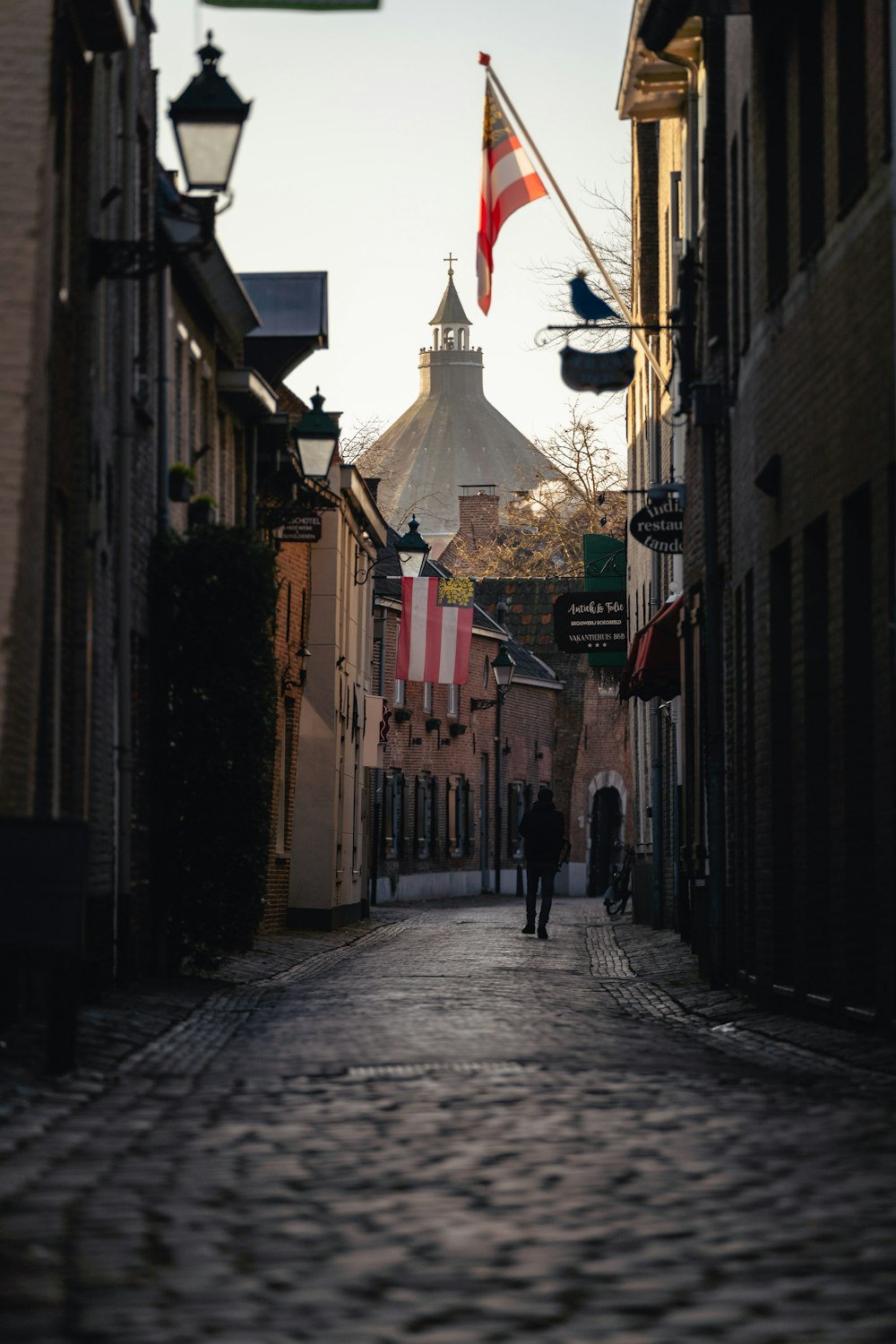 a cobblestone street with flags flying in the wind