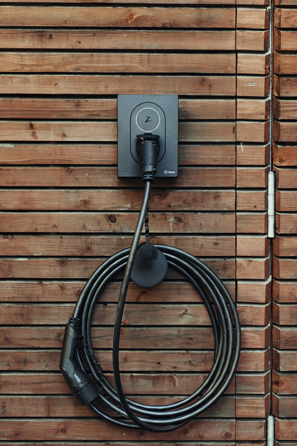 a black cord plugged into a wooden wall