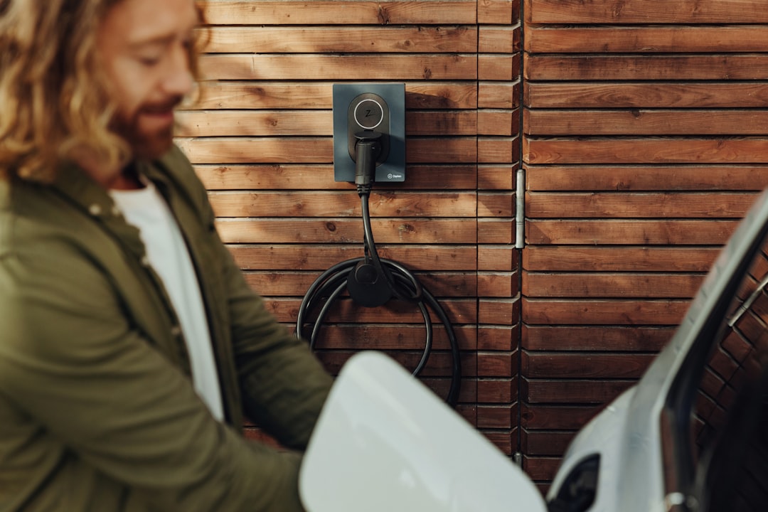 a man standing next to a white toilet in front of a wooden wall, The beautifully designed and amazing Zaptec Go, home charger for electric cars. photographer: Joel Heyd