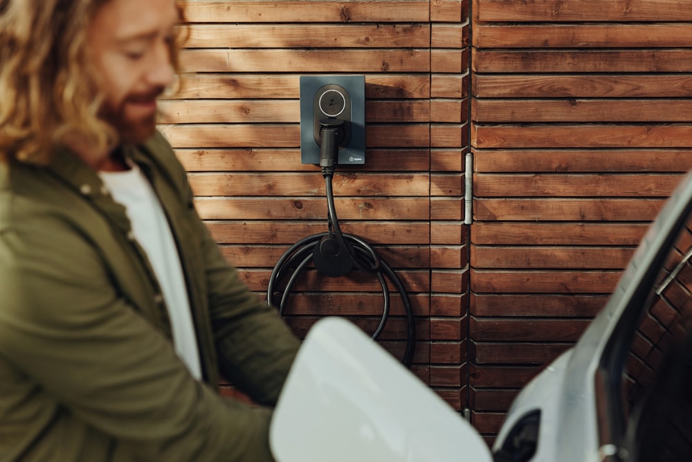 a man standing next to a white toilet in front of a wooden wall