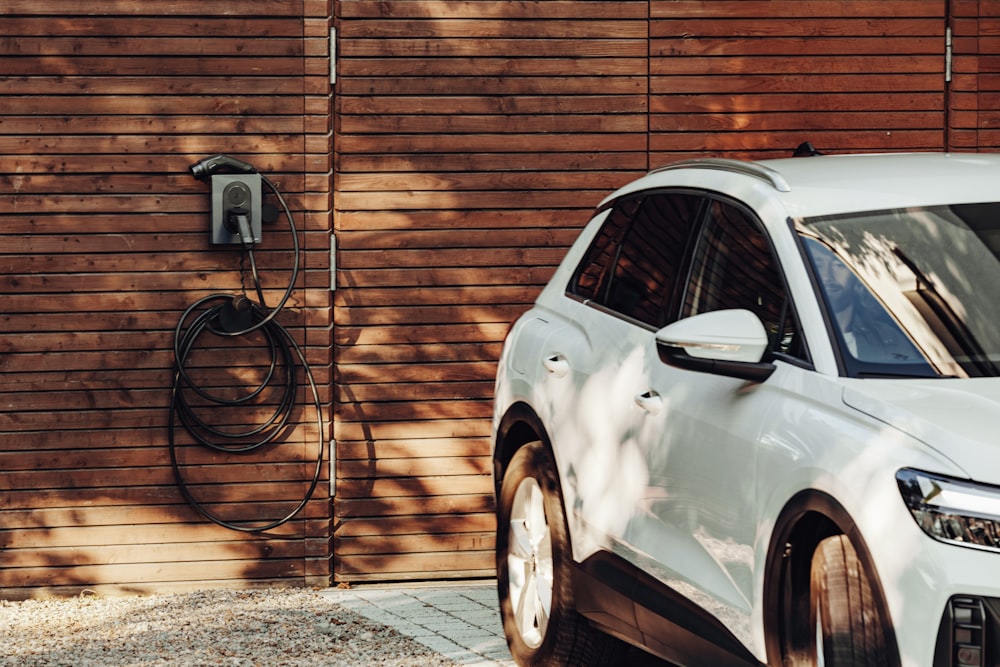 a white car parked in front of a wooden wall