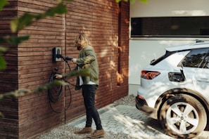 a man is plugging in an electric car to a wooden slatted wall