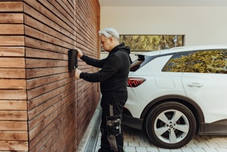 a man in a black jacket and black pants standing next to a white car