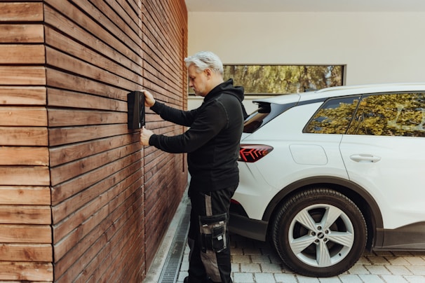 a man in a black jacket and black pants standing next to a white car