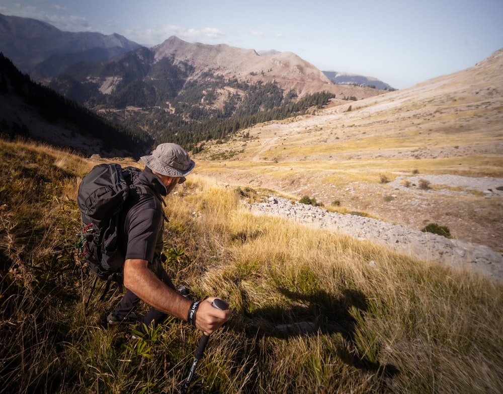 a man kneeling down in a field with mountains in the background