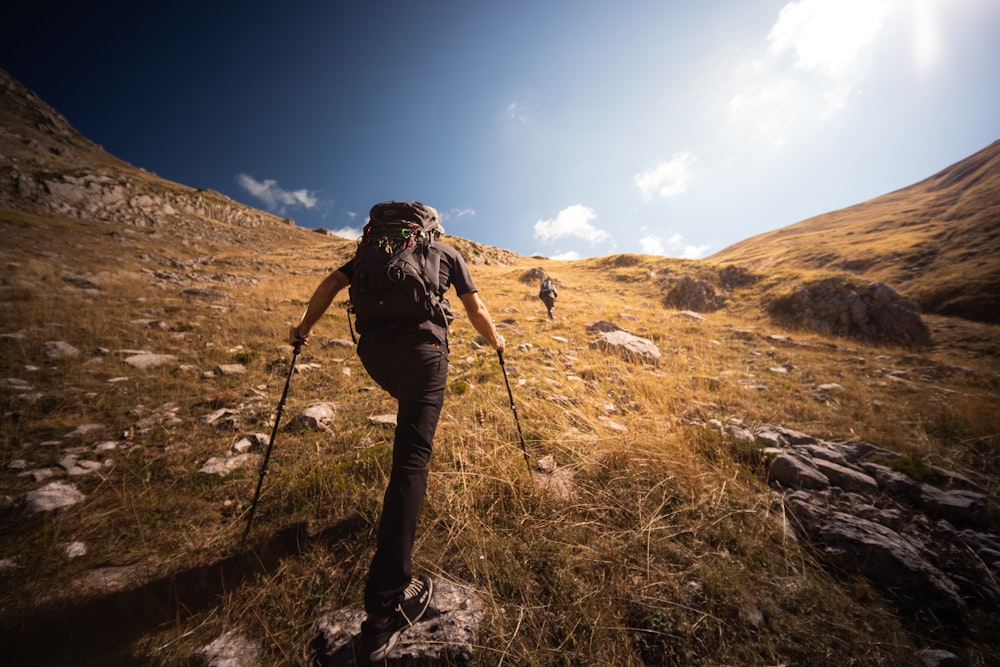 two people hiking up a hill on a sunny day