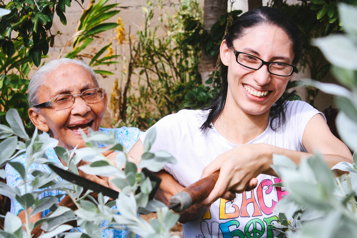 An older woman gardening and smiling together with a younger family member