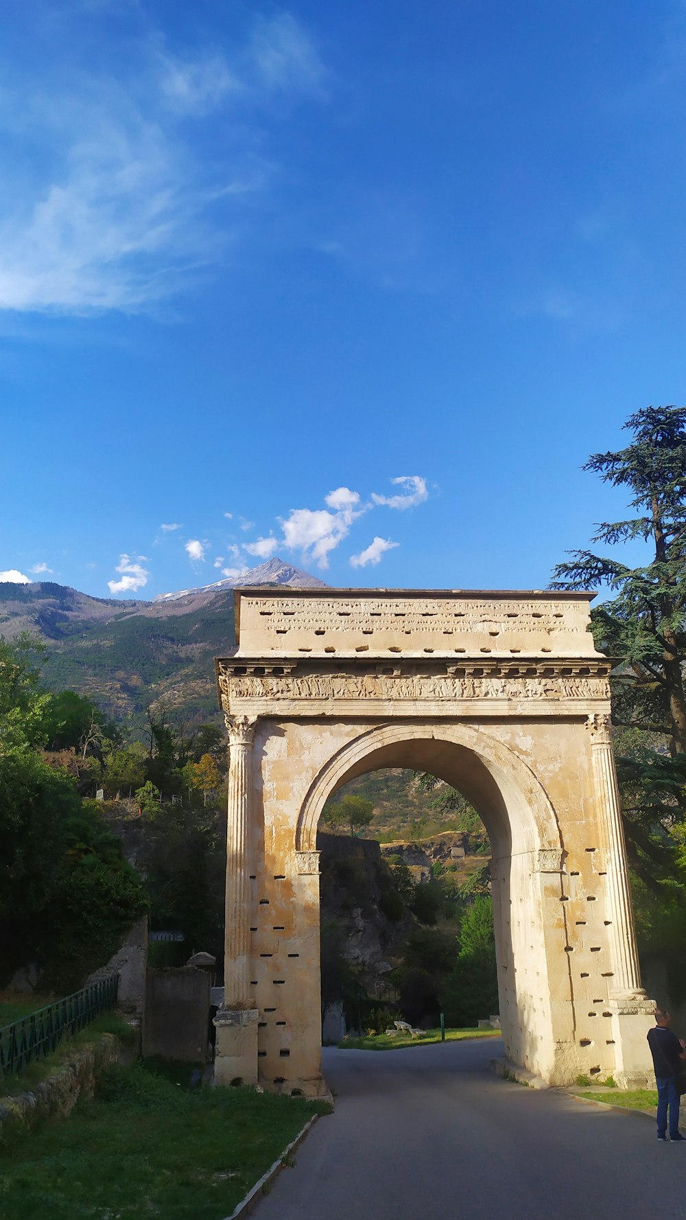 un homme debout devant une arche de pierre