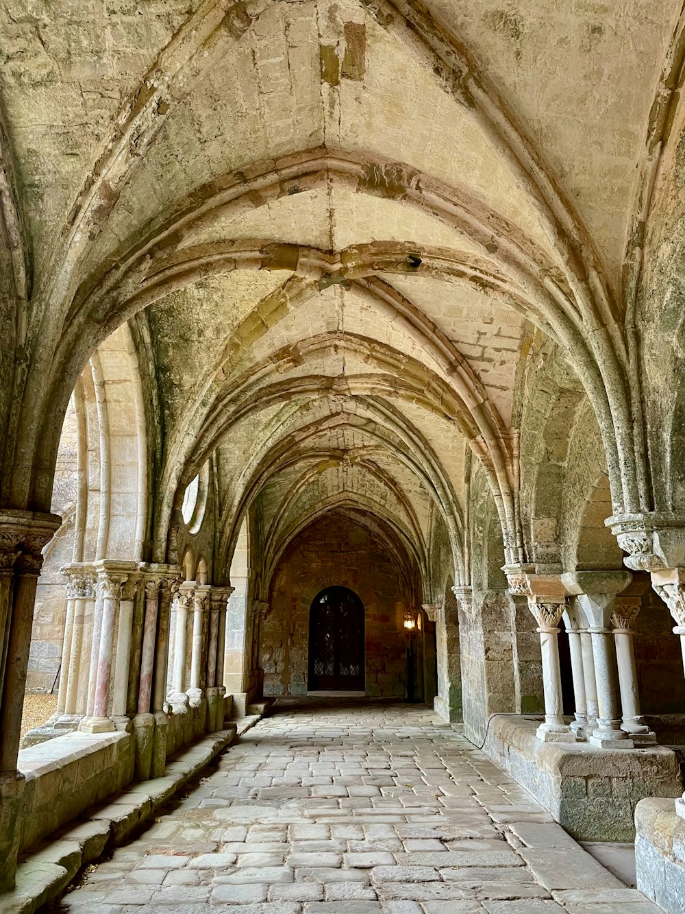 a long hallway with arches and stone flooring