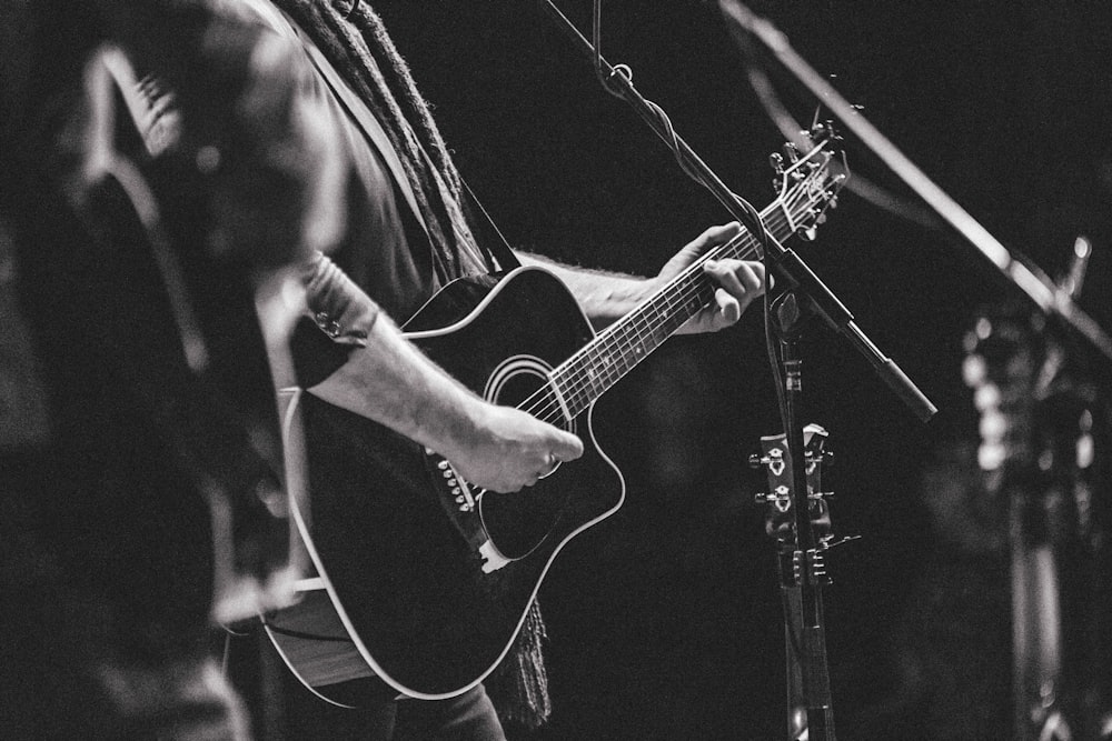 a man playing a guitar in front of a microphone