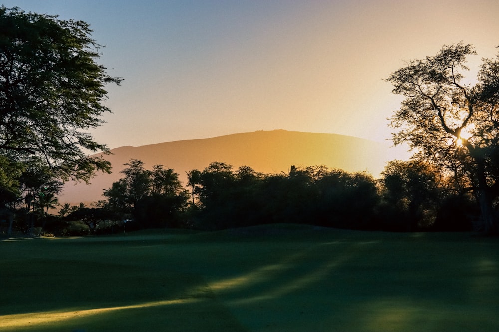 the sun is setting over a golf course