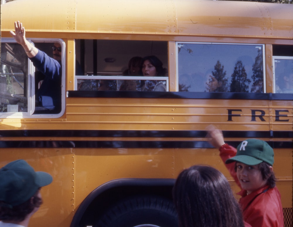 a group of people waving out the windows of a school bus
