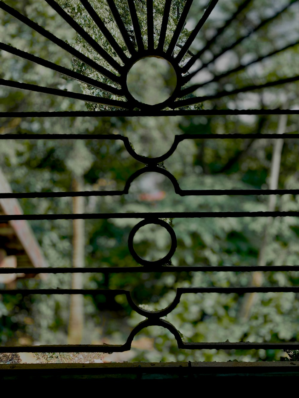 a close up of a metal gate with trees in the background