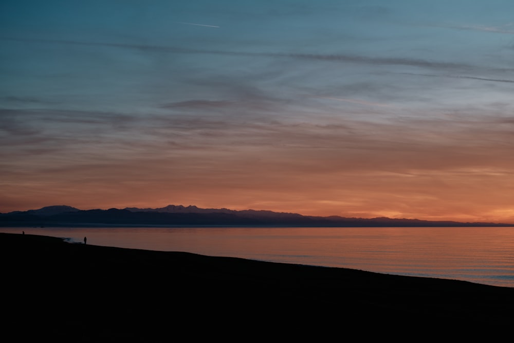 a person standing on a beach watching the sunset