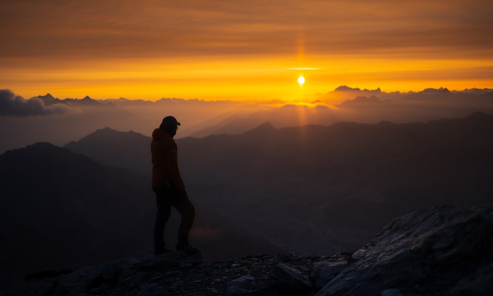 a man standing on top of a mountain at sunset