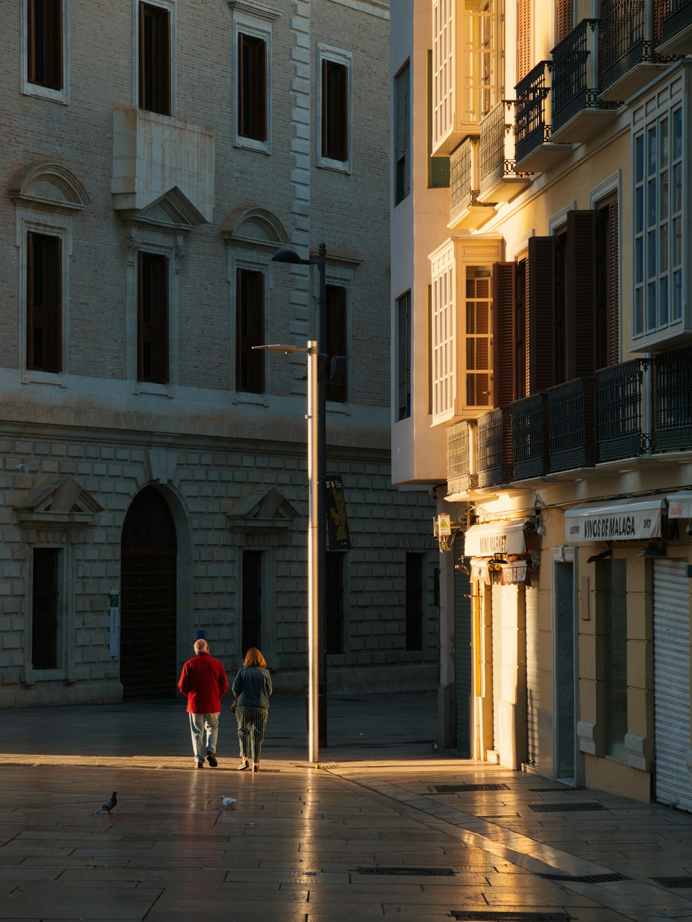 un couple de personnes marchant dans une rue à côté de grands immeubles
