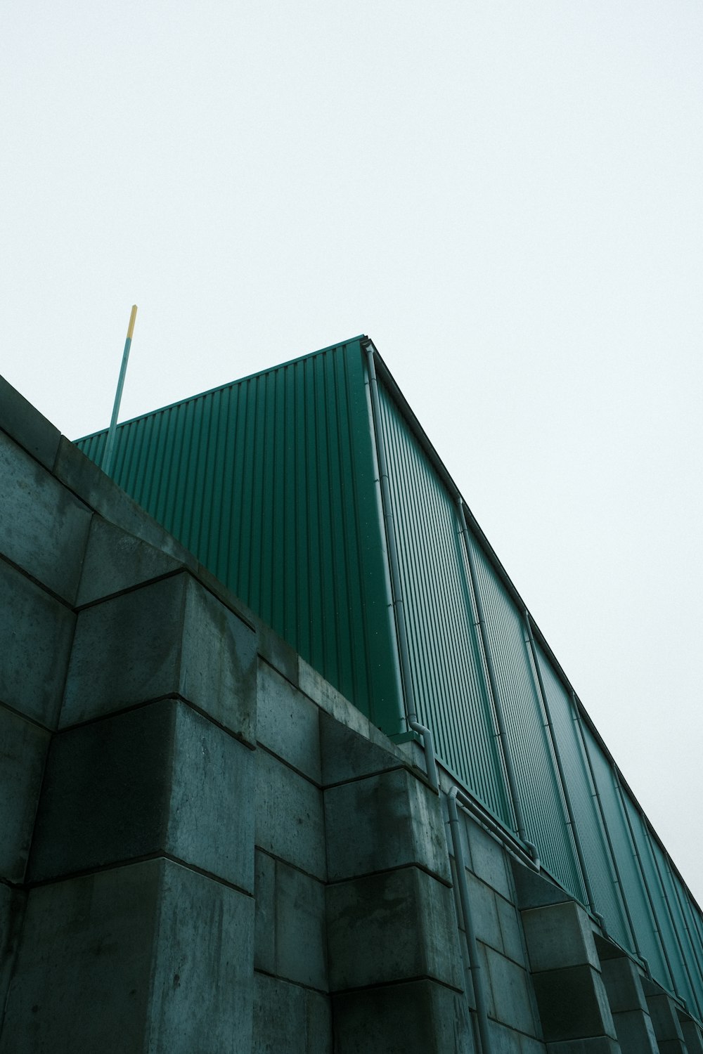 Un edificio con un techo verde junto a una pared
