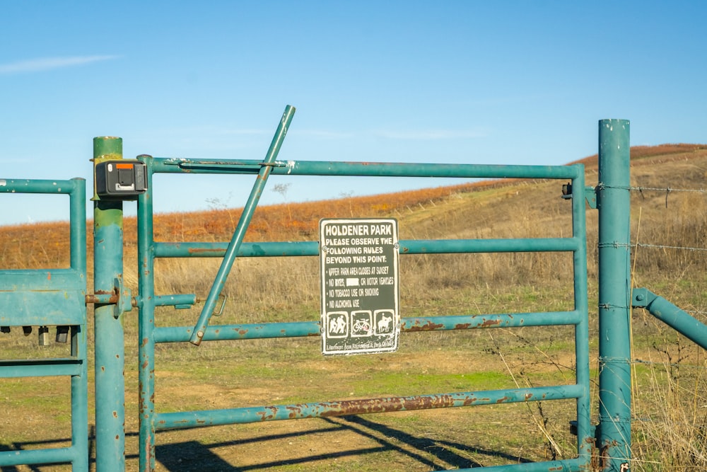 a sign is posted on a gate in a field