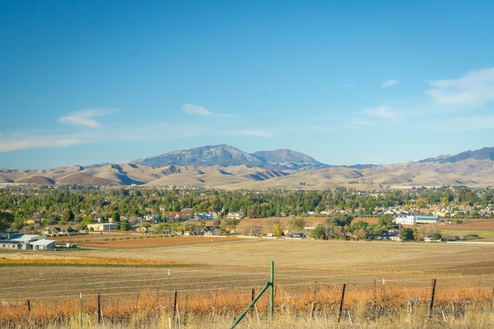 a field with a fence and mountains in the background