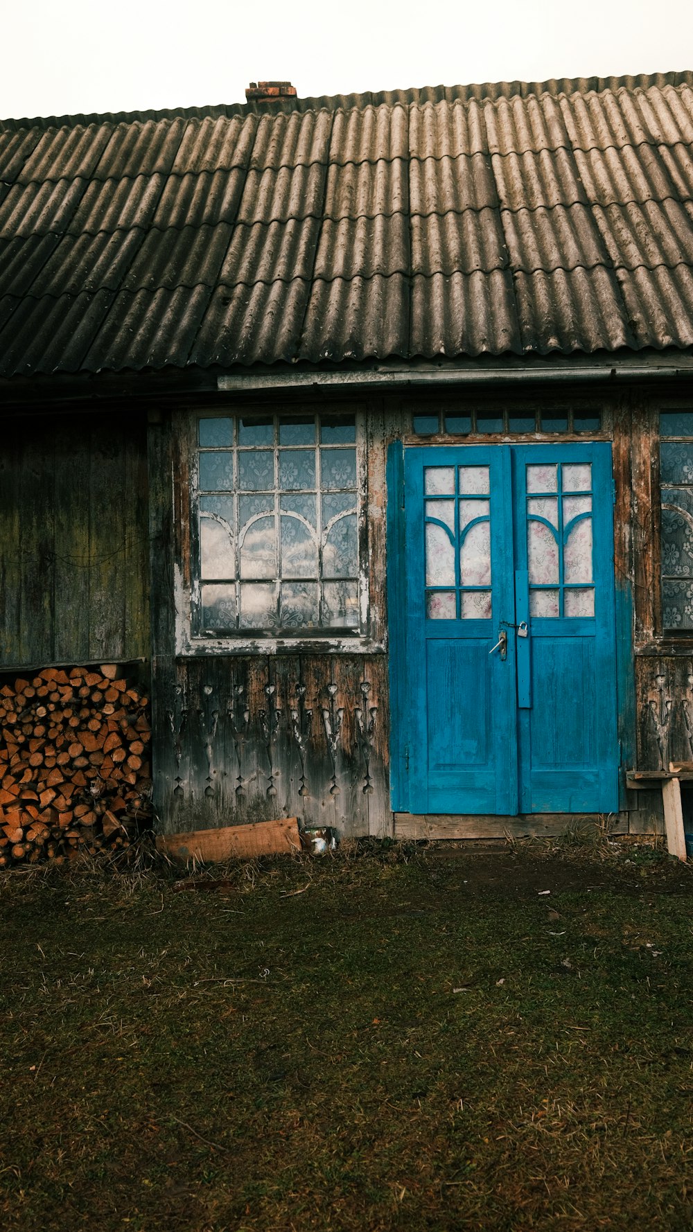 a wooden cabin with a blue door and a stack of logs