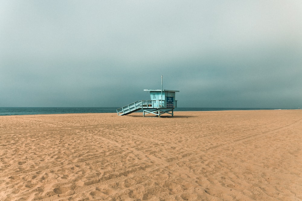 a lifeguard stand on a beach with a cloudy sky