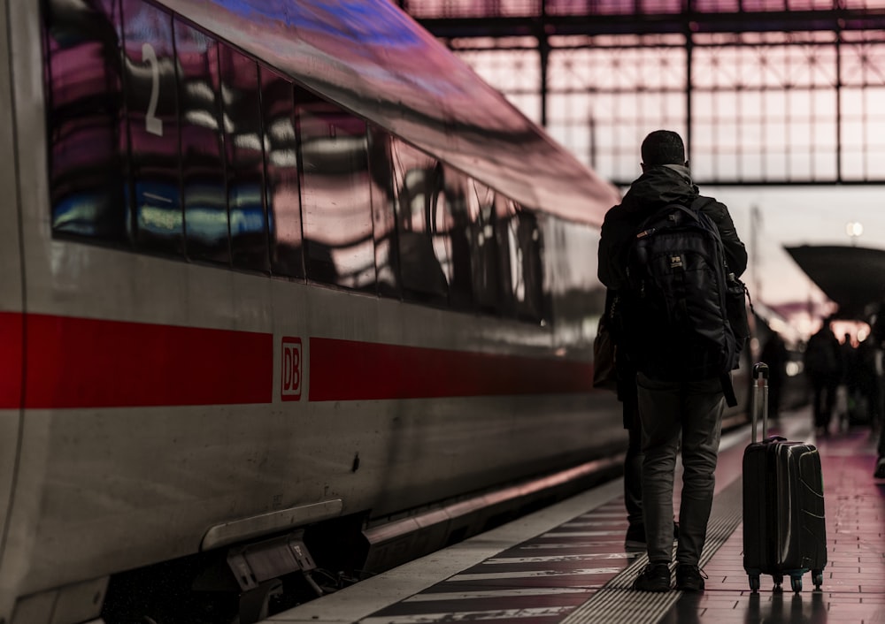 a person with a suitcase walking towards a train