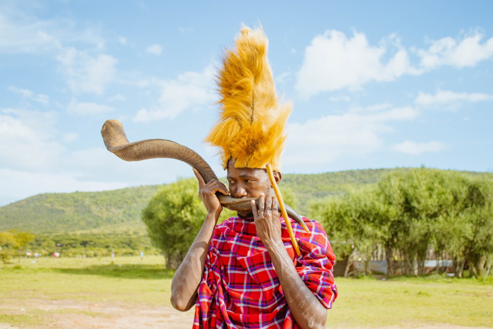a man wearing a yellow feather headdress holding a stick