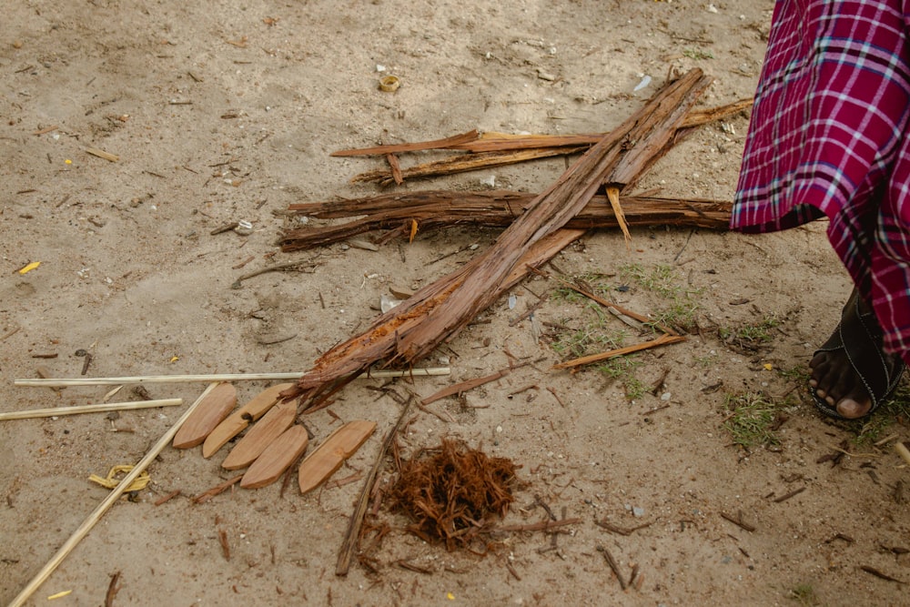 a person standing next to a pile of sticks and sticks