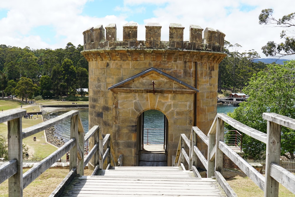 a wooden bridge leading to a stone tower