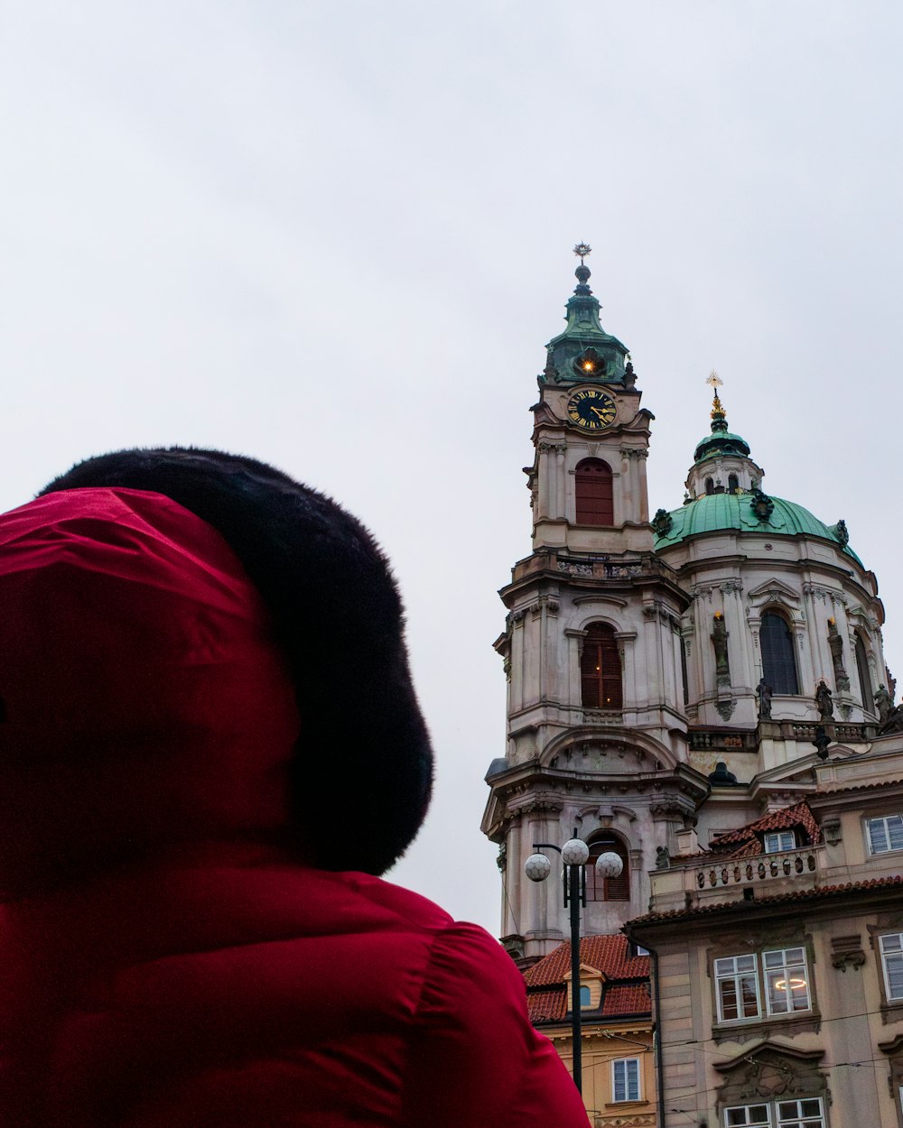 a person in a red coat looking at a building