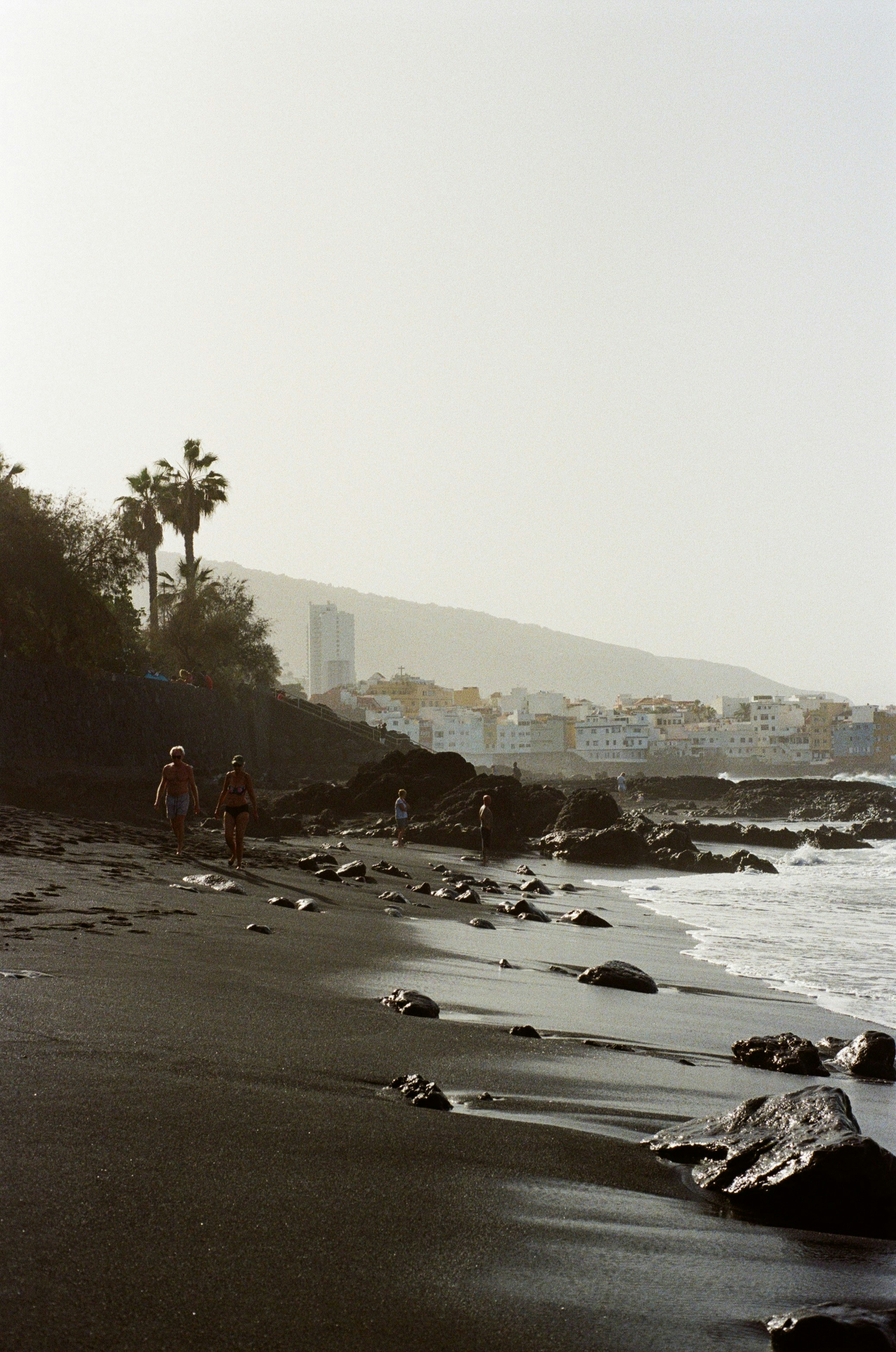 un gruppo di persone che camminano lungo una spiaggia vicino all'oceano
