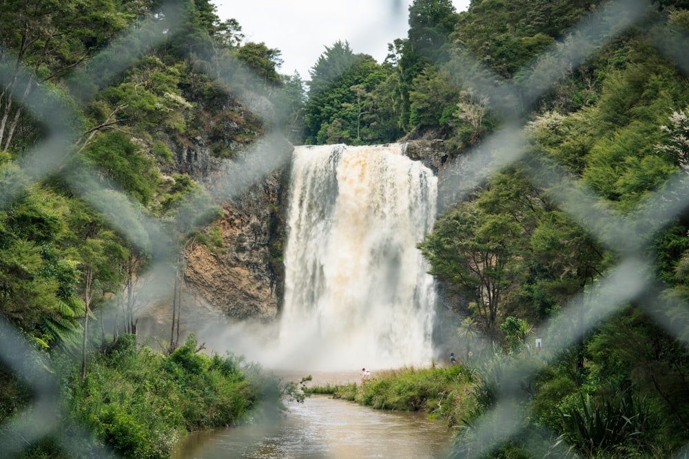 a view of a waterfall through a chain link fence