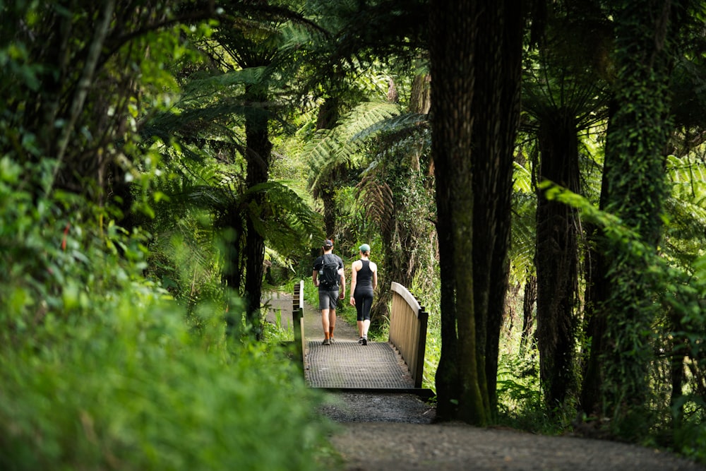 um casal de pessoas caminhando através de uma ponte de madeira