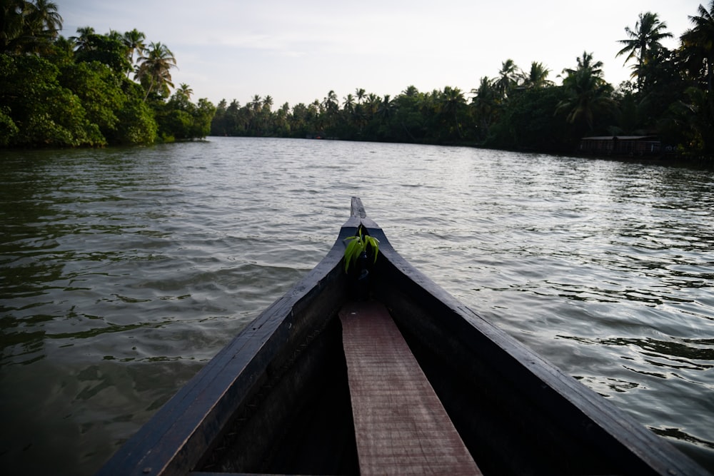 a long boat traveling down a river next to a forest