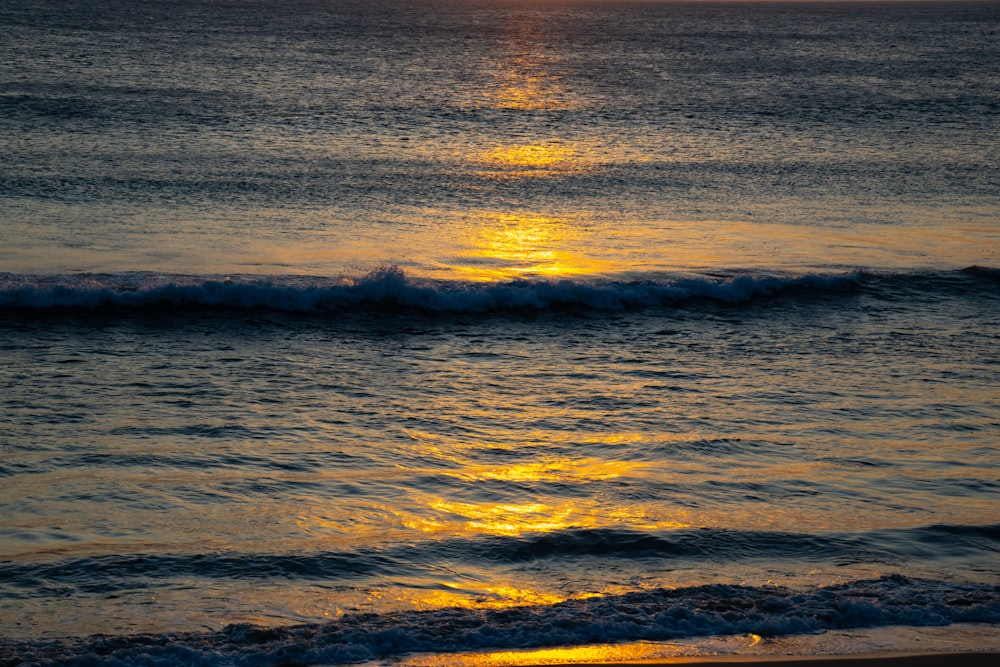 the sun is setting over the ocean waves