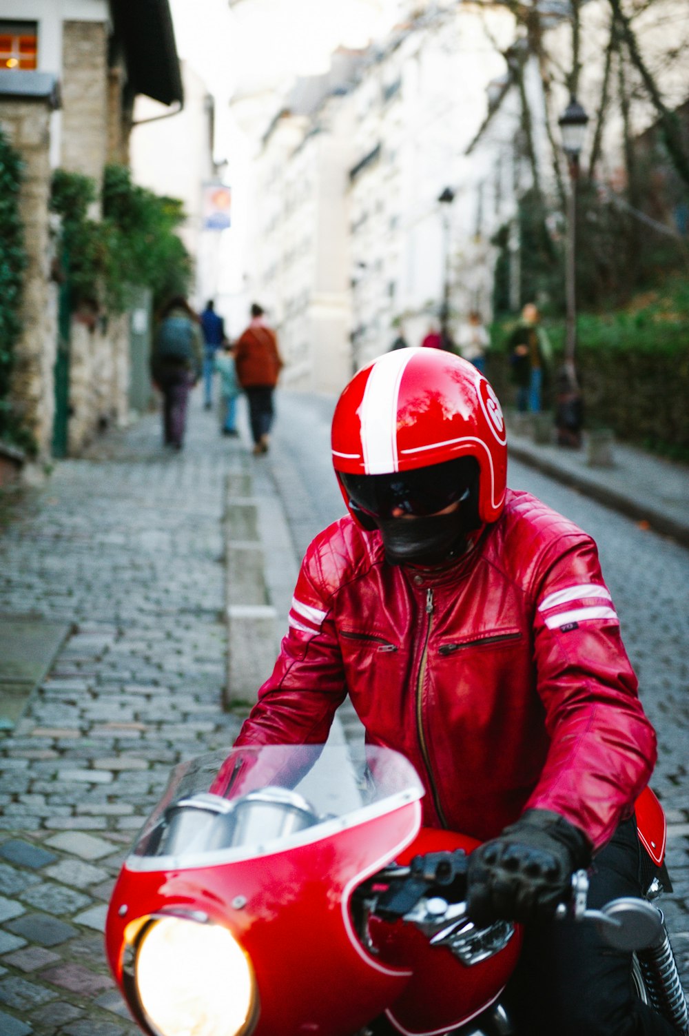 a man riding a red motorcycle down a street